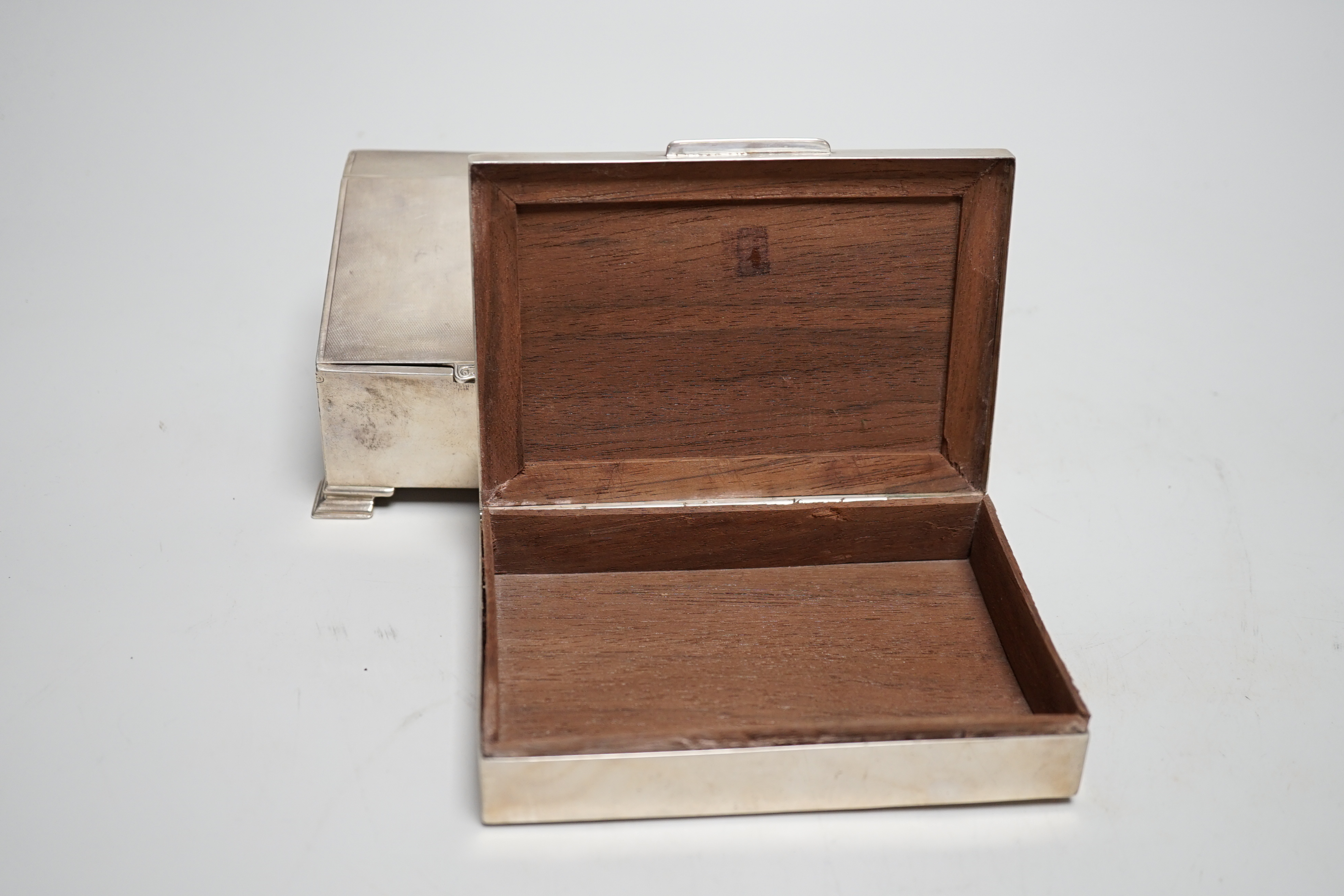 A George V Art Deco engine turned silver twin compartment cigarette box, with slant front, W.I. Broadway & Co, Birmingham, 1929, width 12.3cm, together with an engraved 900 white metal mounted cigarette box.